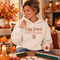 Woman wearing cream Cozy Season Mahj Reason hoodie in a warm fall mahjong setting